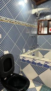 a bathroom with a black toilet and a sink at Hostel das fadas in Paraty