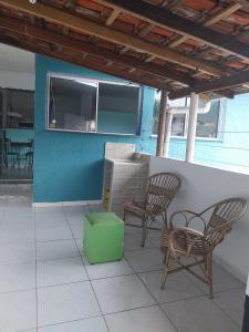 a patio with two chairs and a green ottoman at Casa em Ubatuba perto da praia in Ubatuba