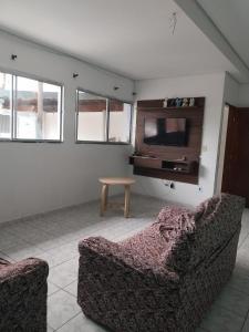 a living room with a couch and a tv at Casa em Ubatuba perto da praia in Ubatuba