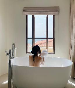 a woman sitting in a bath tub in a bathroom at Mellon OASIS Phu Quoc in Phu Quoc
