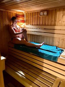 una mujer sentada en el interior de una sauna en Kis Szárcsa Vendégház, en Gárdony