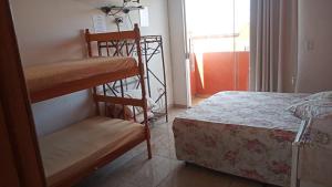 a bedroom with a bunk bed and a bed and a window at Pousada Iguape Apartamentos - Unidade Ilha Comprida in Ilha Comprida