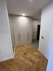 une pièce vide avec des armoires blanches et du parquet dans l'établissement Modern apartment in Košice, à Košice