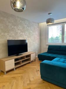 un salon avec un canapé bleu et une télévision dans l'établissement Modern apartment in Košice, à Košice