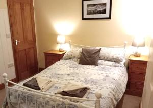 um quarto com uma cama branca com duas mesas de cabeceira em Bwthyn Bach (Tiny Cottage) em Wrexham