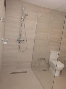 a bathroom with a toilet and a glass shower stall at Höhlenapartment in Güimar