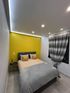 - une chambre avec un lit et un mur jaune dans l'établissement Black Eagle Apartment, à Dráma