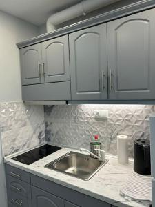 encimera de cocina con fregadero y armarios blancos en Black Eagle Apartment en Dráma