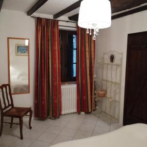 1 dormitorio con cortinas rojas, silla y ventana en Gîte Rozies Dunes 6 p, en Dunes