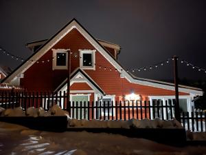 czerwony dom z płotem i światłami świątecznymi w obiekcie Wioska w Sowich Sokolec w mieście Sokolec