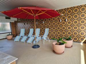 a group of chairs and an umbrella in a room at FeWo Inselblick mit Schwimmbad - Horumersiel in Horumersiel