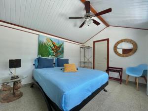 a bedroom with a blue bed with a ceiling fan at Huahine Beach House in Fare