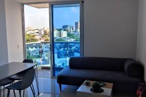 sala de estar con sofá y ventana grande en Acogedor apartamento en exclusivo barrio de Barranquilla, en Barranquilla