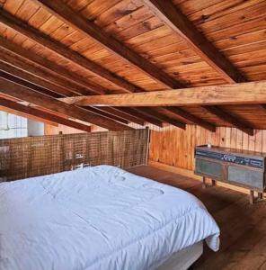 um quarto com uma cama e um tecto de madeira em El_Ceibo_Lobos em Lobos