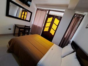um quarto com uma cama, uma mesa e janelas em TintayaHotel em Chachapoyas