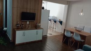 a living room with a tv on a cabinet and a table at Guarapari Apolo Confort in Guarapari