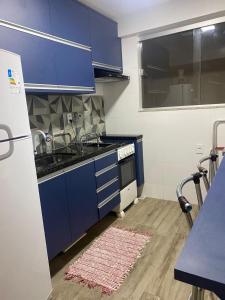 a kitchen with blue cabinets and a sink at Guarapari Apolo Confort in Guarapari +8 photos
