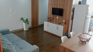 a living room with a couch and a tv at Guarapari Apolo Confort in Guarapari