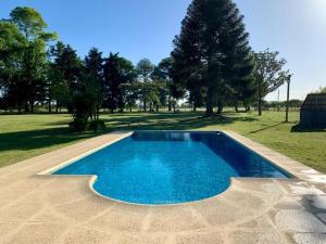 una piscina azul en un campo con árboles en La Rosada Casa de Campo en General Las Heras