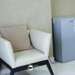 uma cadeira branca com uma almofada ao lado de um frigorífico em Hotel Mirador Del Golfo em Las Grutas