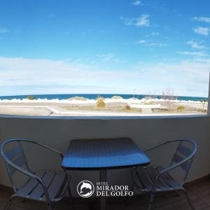 Hotel Mirador Del Golfo في لاس غروتاس: طاولة وكراسي أمام نافذة مع الشاطئ