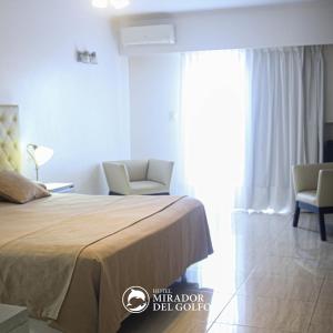 a bedroom with a bed and two chairs and a window at Hotel Mirador Del Golfo in Las Grutas