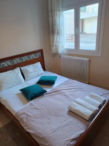 a bedroom with a bed with two pillows and a window at House next to the sea side in Derveni