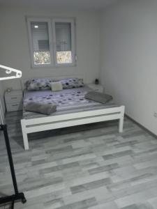 Apartment B&E في توزلا: سرير في غرفة بيضاء مع نافذة