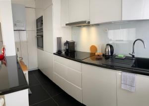 una cucina con armadi bianchi e piano di lavoro nero di Zwarte Arend AirBnB ad Anversa