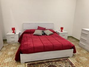 una camera con letto rosso e 2 comodini di La Mimosa Case Vacanze a Marsala
