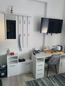 a white desk with a chair and a tv on a wall at Comfort Stay, EV, Parking in Bolesławiec
