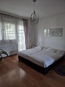 Un dormitorio con una cama grande y una lámpara de araña. en Orchidea Apartman, en Gödöllő