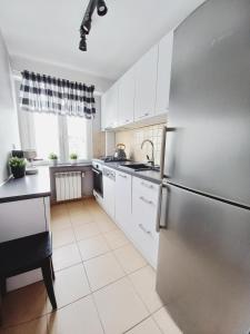 a kitchen with white cabinets and a stainless steel refrigerator at Dobre Sny na Konopnej in Bydgoszcz