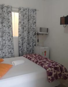 a bedroom with a bed with a blanket on it at Pousada Iguape Apartamentos - Unidade Ilha Comprida in Ilha Comprida