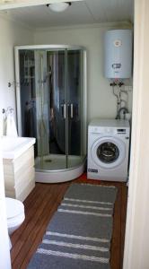 a bathroom with a shower and a washing machine at Scoutstugan in Falun