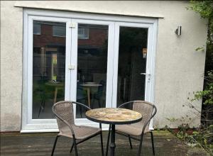 a table and two chairs and a table and a glass door at Cosy yet spacious bungalow in Saughall