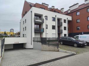 een zwarte auto geparkeerd voor een wit gebouw bij Nova Town Apartament in Stargard