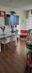 sala de estar con mesa de cristal y sillas en Departamento a pasos del Faro, en La Serena