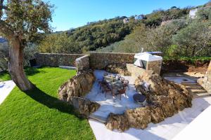 un jardín con mesa, sillas y pared de piedra en Villa Jarito, en SantʼAgata sui Due Golfi