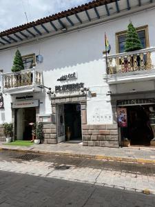 a white building with a balcony on a street at Hotel Plateros in Cusco