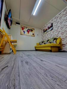 Habitación con sofá amarillo y pared de ladrillo en Tiny House Căsuța cocoțată - Valea Doftanei - 2camere, en Valea Doftanei