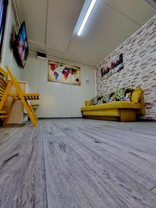 a room with a yellow couch and a brick wall at Tiny House Căsuța cocoțată - Valea Doftanei - 2camere in Valea Doftanei +14 photos
