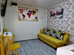 a living room with a yellow couch and some paintings at Tiny House Căsuța cocoțată - Valea Doftanei - 2camere in Valea Doftanei