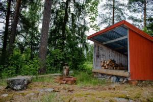 een rood gebouw met een stapel houtblokken in een bos bij Bagarstugan in Falun