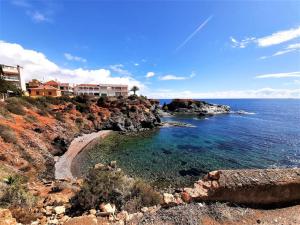 a house on top of a cliff next to the ocean at Apartamento Calypso in Cabo de Palos