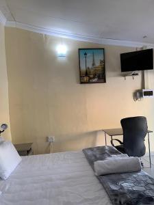 a bedroom with a bed and a chair and a tv at Mudix Royal Palace Guest Lodge in Musina