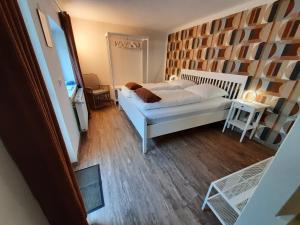 Schlafzimmer mit einem weißen Bett und Holzboden in der Unterkunft Diana's Stube in Krefeld