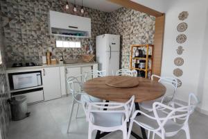 a kitchen with a wooden table and white chairs at Casa Silandia, tu casa en Búzios in Búzios