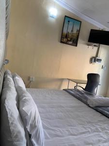 um quarto com uma cama branca e uma televisão na parede em Mudix Royal Palace Guest Lodge em Musina