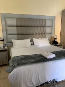 um quarto com uma cama grande e uma grande cabeceira. em Mudix Royal Palace Guest Lodge em Musina